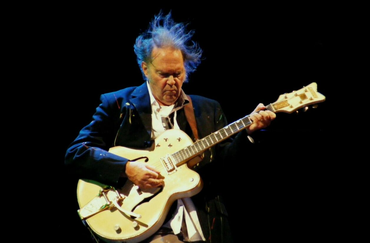 Neil Young en plein riff de guitare lors d'un concert en 2012